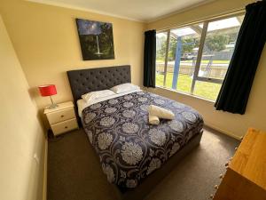 a bedroom with a bed and a window at Relaxing Raglan & the Boat House in Raglan