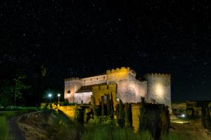 an old castle is lit up at night at Posada Real Castillo del Buen Amor in Villanueva de Cañedo