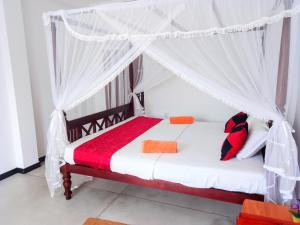 a bedroom with a bed with a mosquito net at Near Beach Rest in Unawatuna