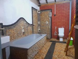 une salle de bain avec baignoire et toilettes dans l'établissement Sandalwood Family Cottages, à Uda Walawe
