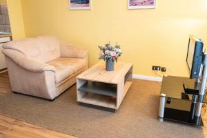 - un salon avec une chaise et une table fleurie dans l'établissement Haus-Ornum-1-OG-O-Wohnung-13, à Westerland