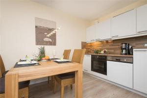 a kitchen with a wooden table and white cabinets at Tunghoern-Hues-1OG-Wohnung-04 in Keitum