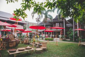 a group of tables and chairs with red umbrellas at Ruen Come In in Chiang Mai