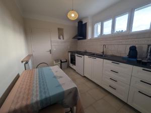 eine Küche mit weißen Schränken und einem Tisch darin in der Unterkunft Confort en famille proche de Giffaumont - FR-1-611-112 in Braucourt + 12 Fotos