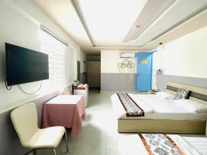 a room with two beds and a table and a tv at Sao Khue Riverside Hotel & Coffee in Sa Ðéc