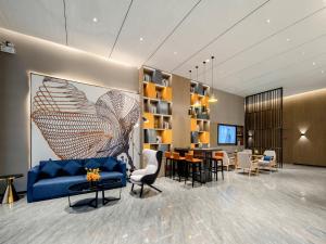 Una sala de estar con un sofá azul y un comedor. en Echarm Hotel Fangchenggang Administration Center High Speed Railway Station, en Gongche