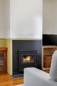 a fireplace in a living room with a fire in it at Wentworth Falls Cottage in Wentworth Falls +11 photos