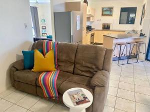 a brown couch with colorful pillows and a table in a kitchen at Charming Abode on Brenton in Tropical North Queensland in Night jar