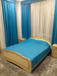 アドレルにあるKlyuchevoy 9 Guest Houseのベッドルーム1室(青いシーツと青いカーテンのベッド1台付)