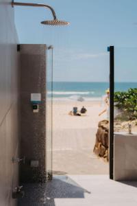 a bathroom with a shower with the beach in the background at On The Beach Noosa Resort in Noosa Heads
