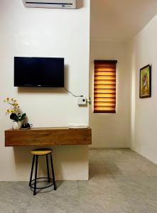 a flat screen tv on a wall with a stool at Bảo Ngọc Motel in Làng Me