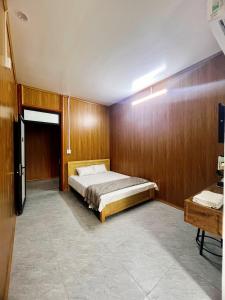 a bedroom with a bed in a room with wooden walls at Bảo Ngọc Motel in Làng Me