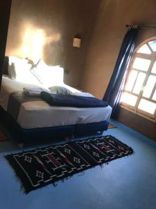 a bedroom with a bed with a rug and a window at Dar Talhaya in Kasr Bounou +24 photos