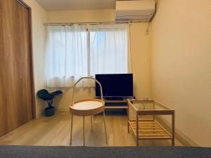 a living room with a tv and a chair in front of a window at BETTEi 別邸 in Okayama