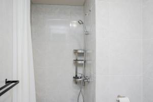 a bathroom with a shower with a shower head at Cozy and Spacious 1BR Apartment at Parkland Avenue By Travelio in Tangerang +15 photos