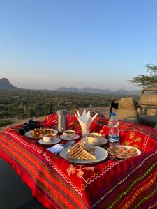 BeraにあるJawai's Wildness Lodgeの赤い毛布の上に食べ物の皿が置かれたテーブル