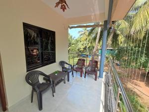 a room with chairs and a table and a balcony at Whispering Waves Luxury Homes in Majorda