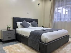 a large bed with a black headboard in a bedroom at Naka Suites With Balcony, Amazing Lake View, GYM in Nakuru