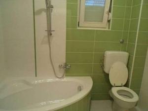 a green tiled bathroom with a toilet and a tub at Apartment Ugljanski gusari - Two Bedroom Apartment with Balcony and Sea view in Ugljan +8 photos