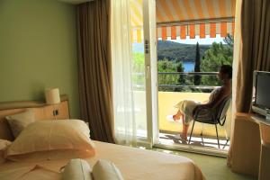 una mujer sentada en una silla junto a una ventana en una habitación de hotel en Hotel Kimen, en Cres