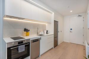Una cocina blanca con fregadero y estufa. en The Alpha Nest Stylish 1BR in Central Wellington, en Wellington