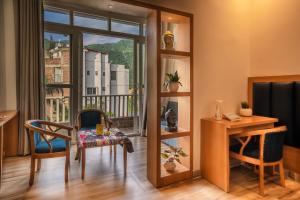 a room with a table and chairs and a balcony at Tripli Hotels Ayushman Retreat in Rishīkesh +83 photos