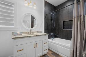 a bathroom with a sink and a tub and a mirror at Modern Cabin Oaklawn in 10 min Private Patio in Hot Springs