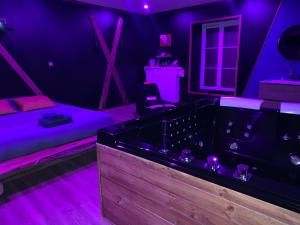 Zimmer mit Whirlpool und lila Beleuchtung in der Unterkunft Love-room l'eden du Désir in Vecqueville