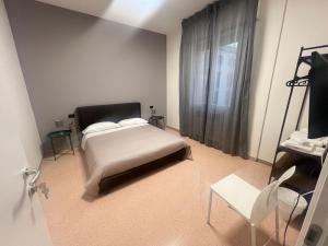 une chambre avec un lit, une chaise et une fenêtre dans l'établissement ManaroomsMarconi, à Bologne