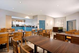 アルバートビルにあるCountry Inn & Suites by Radisson Albertville near Outlet Mallの木製のテーブルと椅子、キッチンを備えたレストラン