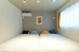 two beds in a small room with a window at River Residence BOTAN by Tranova in Tokyo