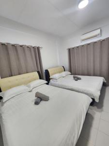 deux lits côte à côte dans une pièce dans l'établissement Sandakan Corner Terrace House, à Sandakan