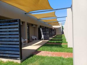 a patio with an umbrella and some grass at DashINN in Viljoenskroon