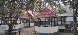 two gazebos with red roofs in a park at Cruise 'N Lake in Kumarakom