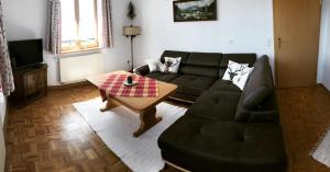 a living room with a black couch and a table at Ferienwohnung Wia Dahoam in Steingädele