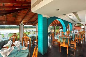 Un comedor con mesas y sillas en un restaurante. en The River Retreat Heritage Ayurvedic Resort, en Shoranūr