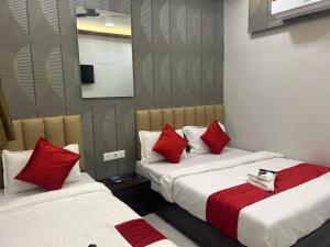 two beds with red pillows in a room at Hotel Vaithi Residency - Andheri West in Mumbai