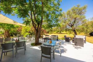 a patio with tables and chairs under a tree at Kosmas Apartments in Roda +36 photos