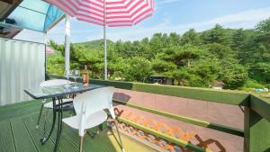 een tafel en stoelen op een balkon met een parasol bij Pocheon Arumdri Pension in Pocheon