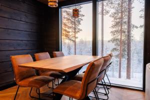 a wooden table and chairs in a room with a large window at Cottage Finland- Levin Hehku B in Levi