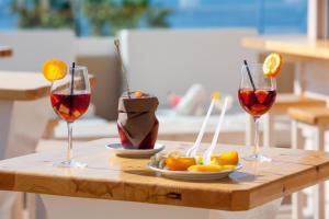 three glasses of wine and a plate of fruit on a table at Aparthotel Los Dragos del Sur in Puerto de Santiago