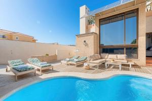 a house with a swimming pool with chairs and a patio at MEDANO4YOU Casa Violeta in El Médano +45 photos