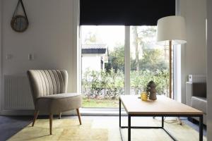 a living room with a chair and a table and a window at Tiny House 'Het Berkenhuisje' in Voorthuizen