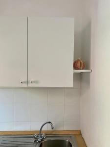 a kitchen with a sink and white cabinets at Casa Estia in Santa Teresa Gallura +11 photos