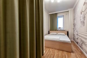 a bedroom with a bed and a green curtain at Абсолютно новая евродвушка у Экспо in Prigorodnyy