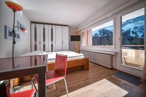 une chambre avec un lit, un bureau et une fenêtre dans l'établissement Paradies 606, à Arosa 1 autre photo