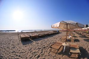a beach with tables and chairs and an umbrella at Hotel Antonella in Lido di Classe