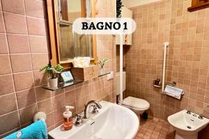 a bathroom with a sink and a toilet and a mirror at Fuori da ZTL - Ideale per Famiglie e Gruppi in Asiago