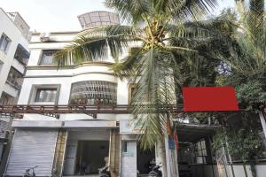 a building with a palm tree in front of it at Super Townhouse The Upper Room Near Pune Airport in Pune