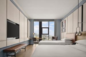 a bedroom with two beds and a desk with a tv at Four Points by Sheraton Datong Pingcheng in Datong